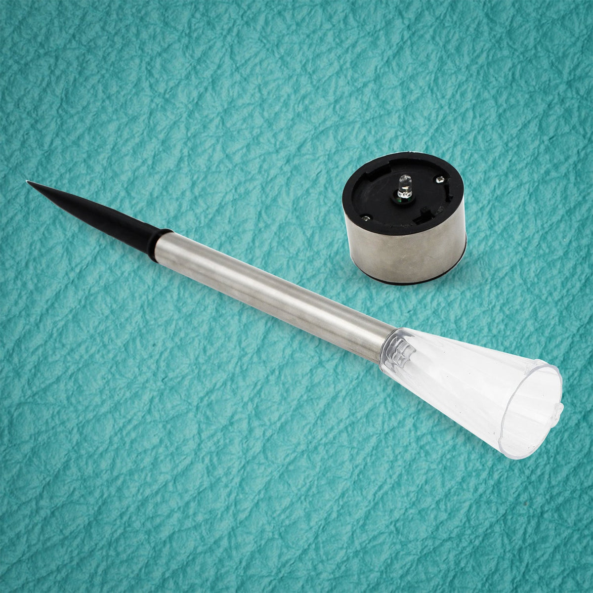 A disassembled solar LED light shows the silver stake with black spike and the separate silver and black solar cap.