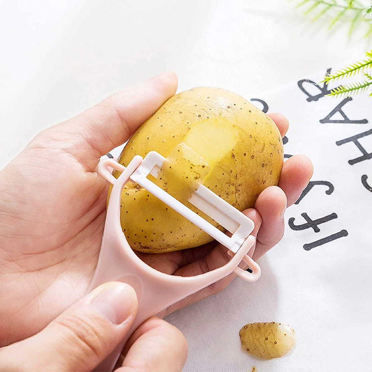 Hand holding the anti-slip handle of the Y-shaped fruit and vegetable peeler.